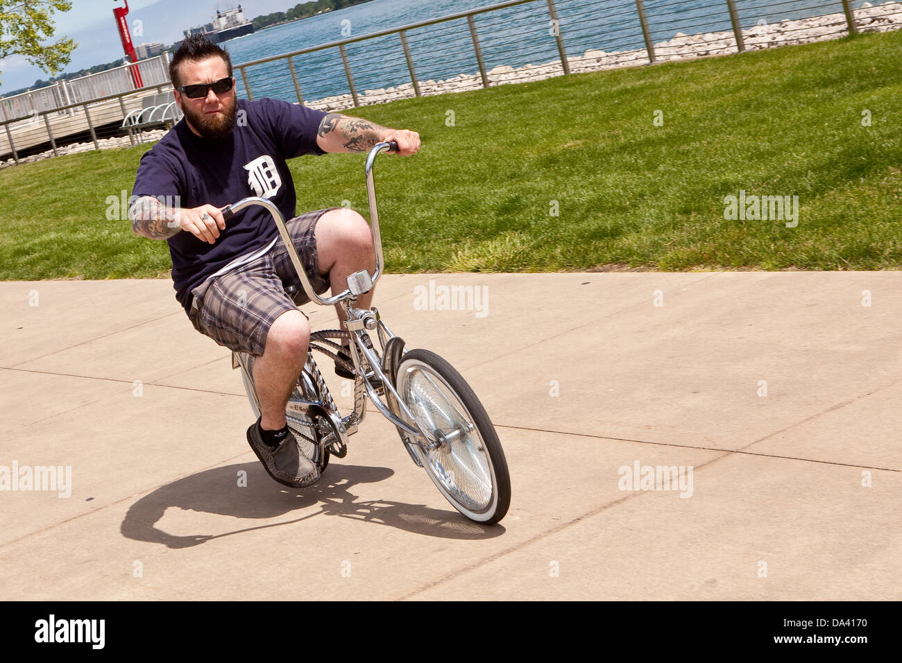 Un uomo corse la sua bici sul lungofiume di Detroit sabato Foto Stock