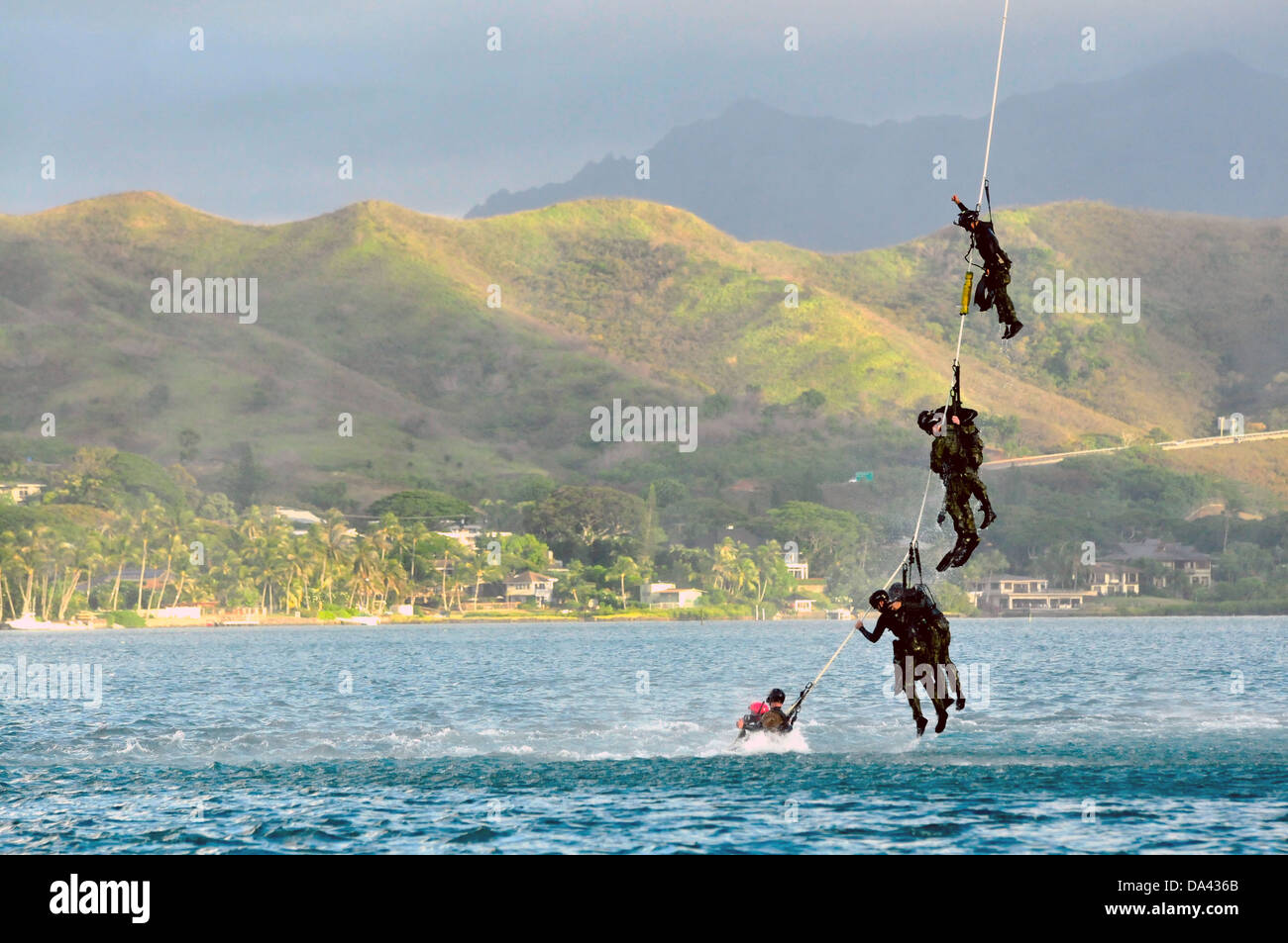 US Navy SEAL i membri del team a penzolare dalla speciale pattuglia di inserimento e di estrazione corda attaccata ad un UH-60 Black Hawk elicottero durante la formazione HELOCAST al Marine Corps Air Station Kaneohe Bay il 19 giugno 2013 nelle Hawaii. Foto Stock