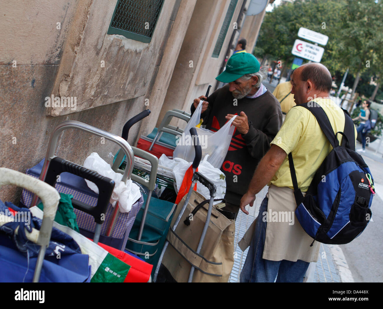 Persone verificare la loro appartiene mentre sono in attesa in una carità la Chiesa per un sacco di beni e cibo a Maiorca, SPAGNA Foto Stock