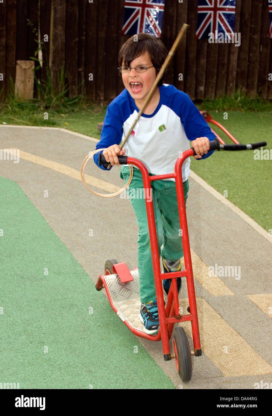 Ragazzo di 7 anni godendo di scooter a un estate fete, foglio, hampshire, Regno Unito. Foto Stock