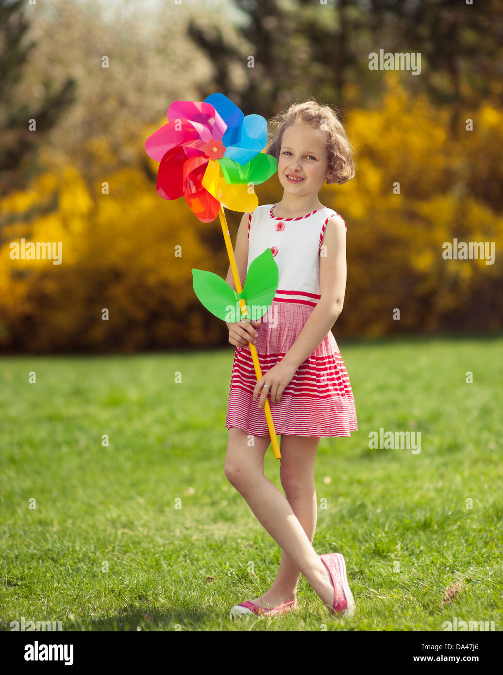 Ragazza giovane azienda grande fiore a forma di ruota del vento Foto Stock