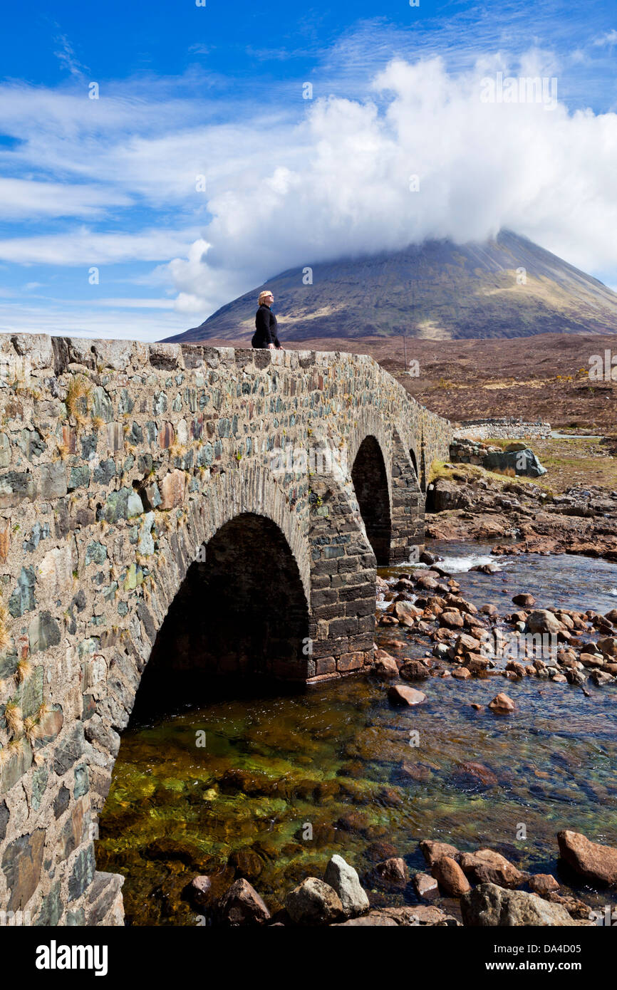 La donna che stava in piedi sul vecchio ponte di Sligachan oltre il fiume sulla isola di Skye delle Highlands e delle isole della Scozia UK GB EU Europe Foto Stock