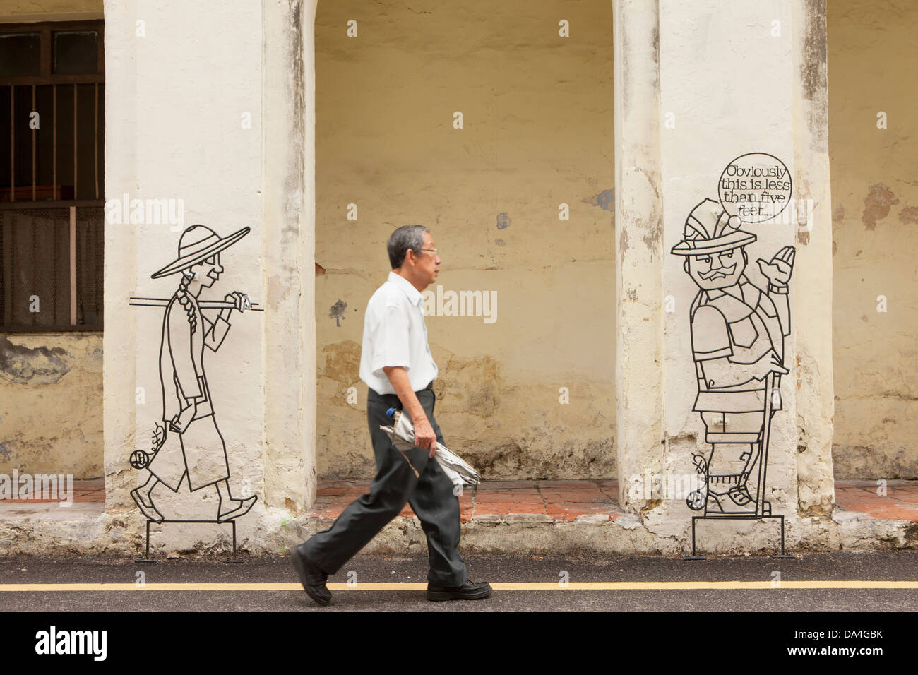 Uomo che cammina passato street art, Georgetown, Penang, Malaysia Foto Stock