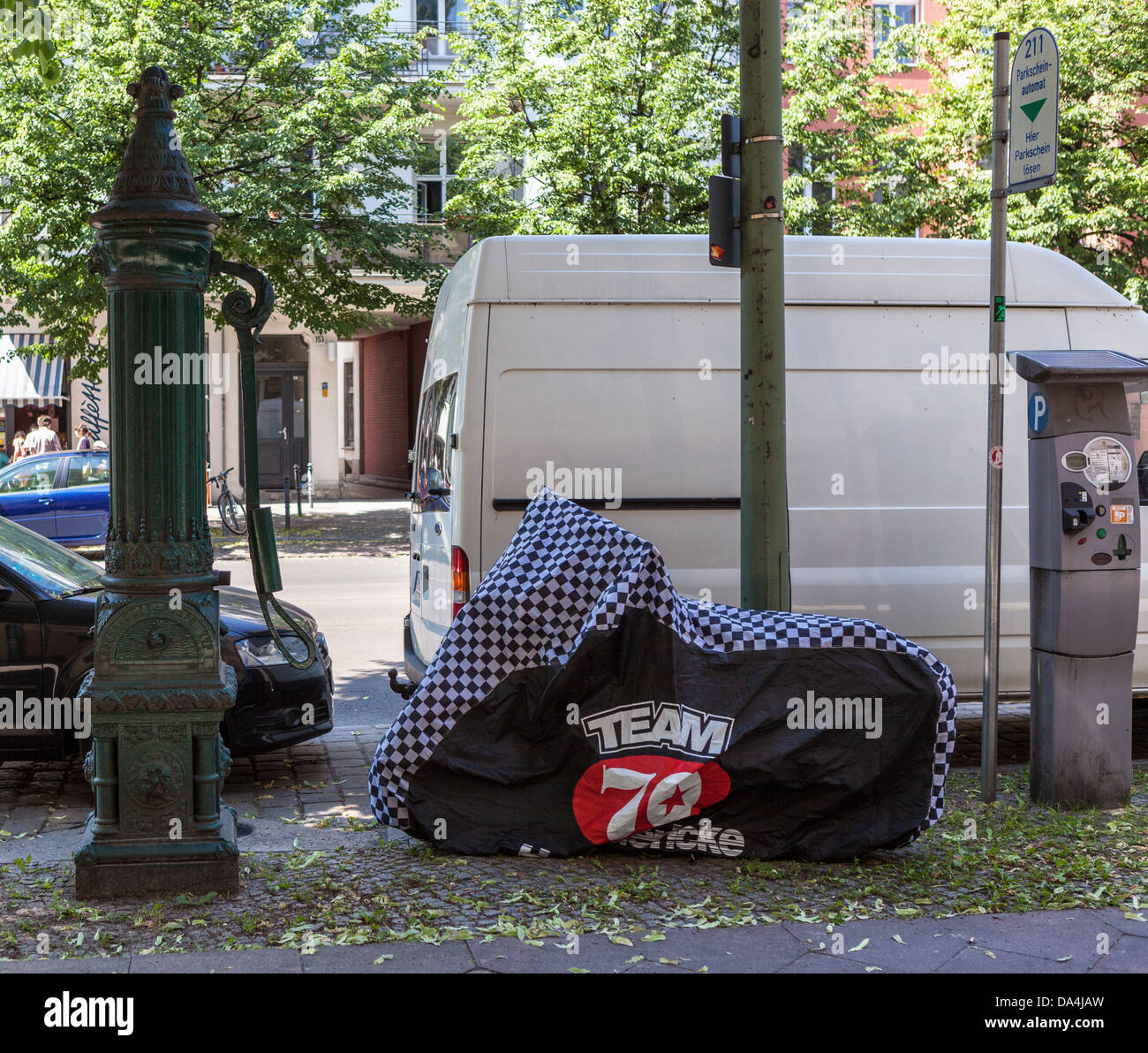 Una pompa a mano fontana potabile e una moto con un 'team 70' coperchio in una strada di Berlino Foto Stock