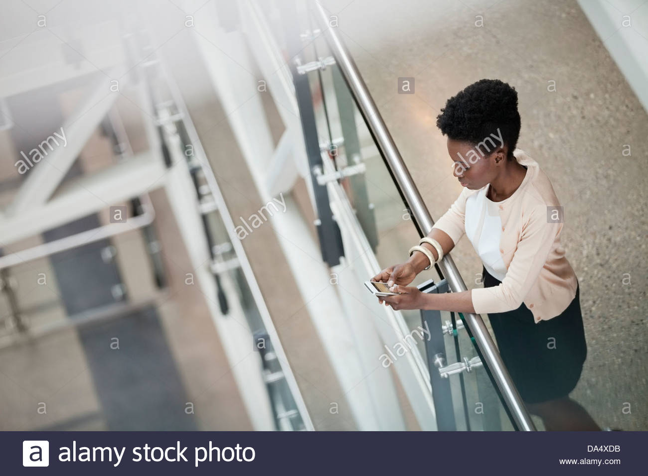 Elevato angolo di visione della donna utilizzando il telefono cellulare per l'edificio degli uffici Foto Stock