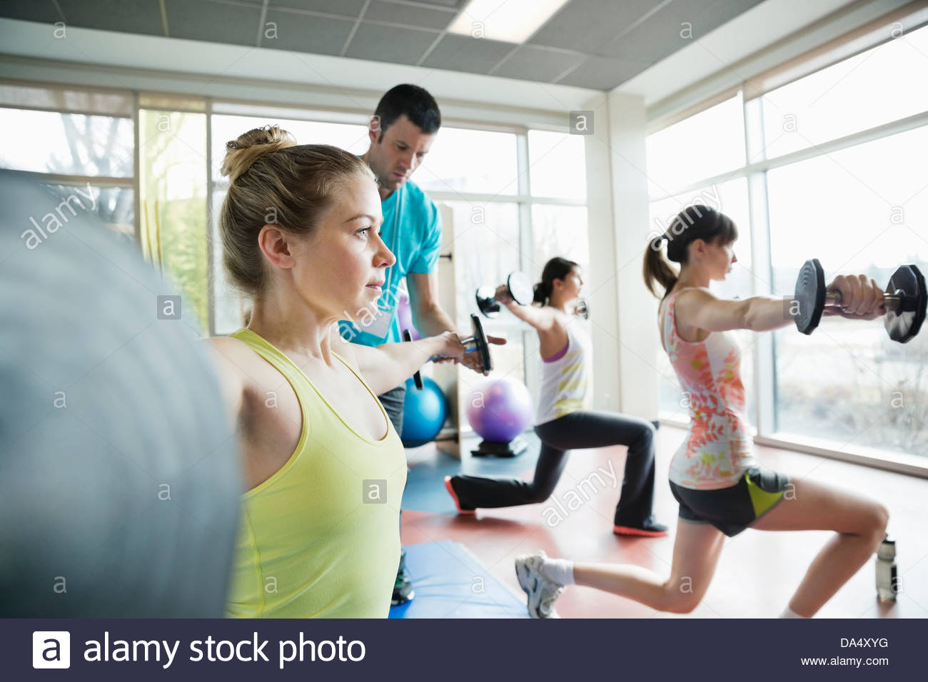 Istruttore assiste donna con esercizio in classe di fitness Foto Stock