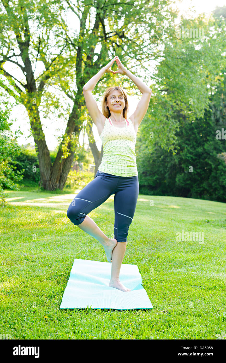 Femmina istruttore di fitness fare yoga albero o vrksasana pongono nel parco verde Foto Stock