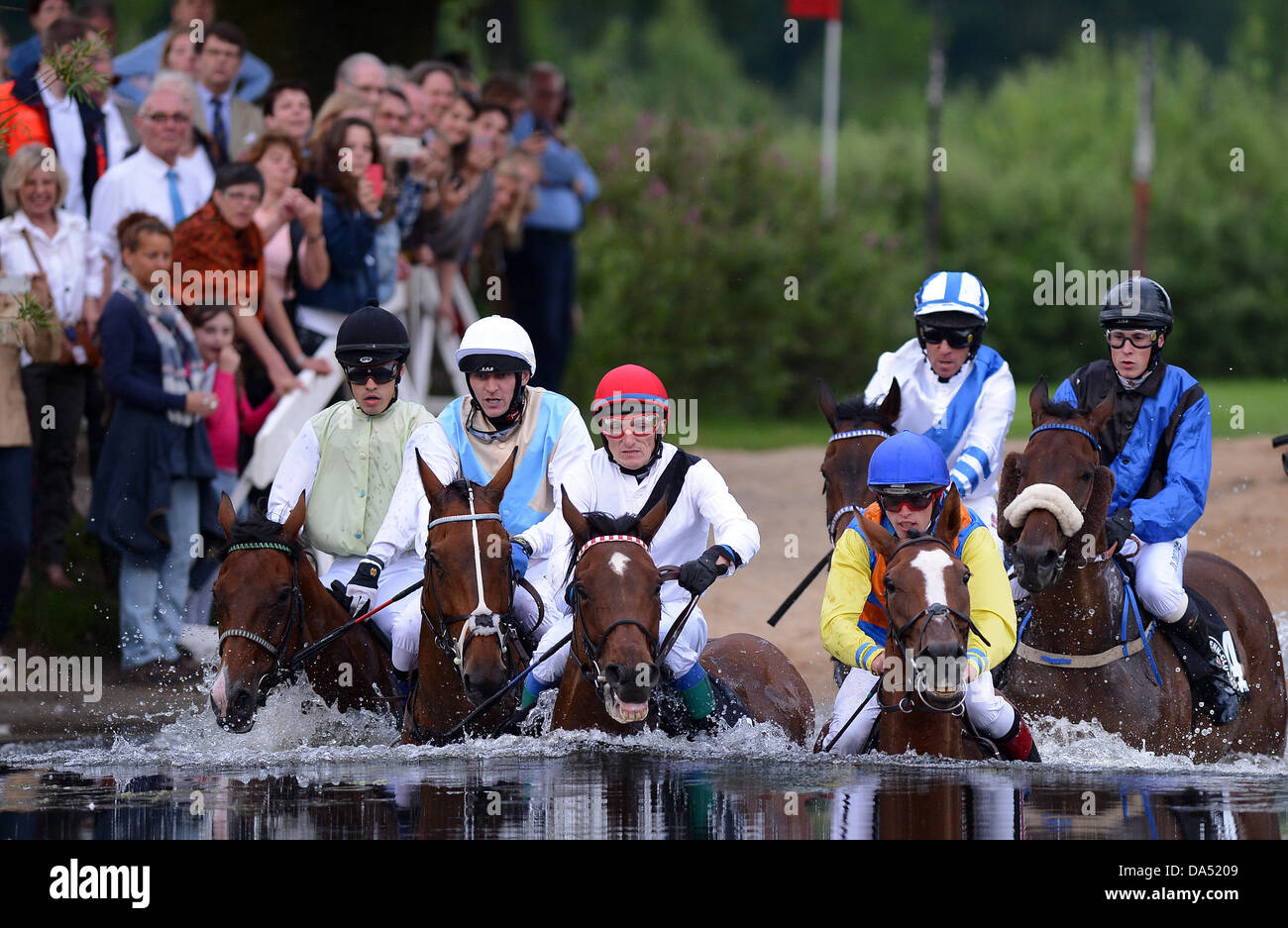 Amburgo, Germania. 03 Luglio, 2013. Cavalli e Cavalieri si traversa un ostacolo di acqua nel lago la gara di suoneria (Seejagdrennen) durante il equina sport galoppo derby incontro al racecourse Hamburg-Horn ad Amburgo, Germania, 03 luglio 2013. Foto: Axel HEIMKEN/dpa/Alamy Live News Foto Stock