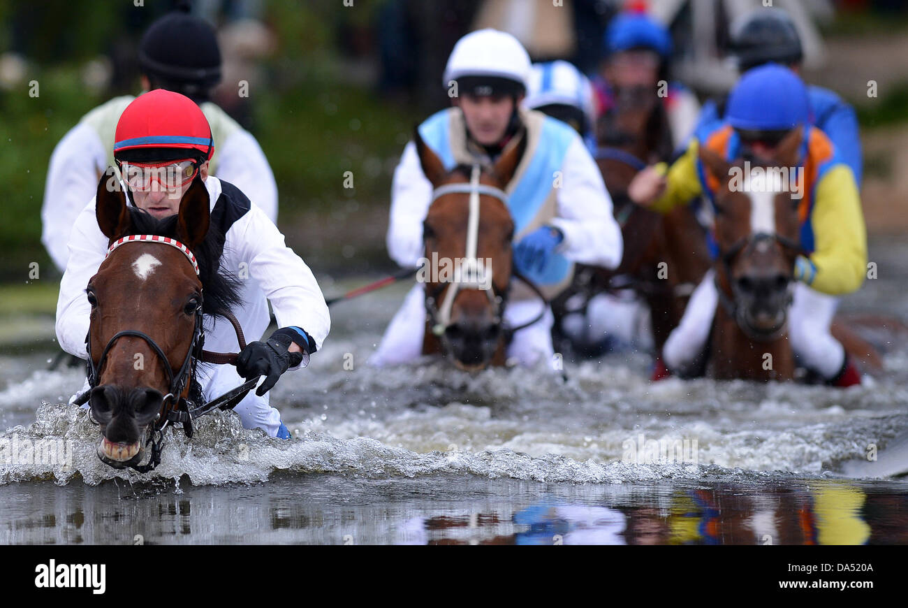 Amburgo, Germania. 03 Luglio, 2013. Cavalli e Cavalieri si traversa un ostacolo di acqua nel lago la gara di suoneria (Seejagdrennen) durante il equina sport galoppo derby incontro al racecourse Hamburg-Horn ad Amburgo, Germania, 03 luglio 2013. Foto: Axel HEIMKEN/dpa/Alamy Live News Foto Stock