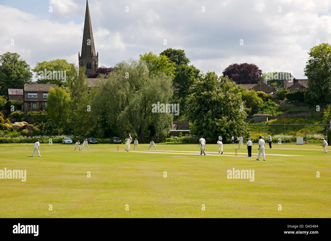 Uomini persone che giocano a partita di cricket sul campo di cricket del villaggio in estate Masham Village North Yorkshire Inghilterra Regno Unito GB Gran Bretagna Foto Stock