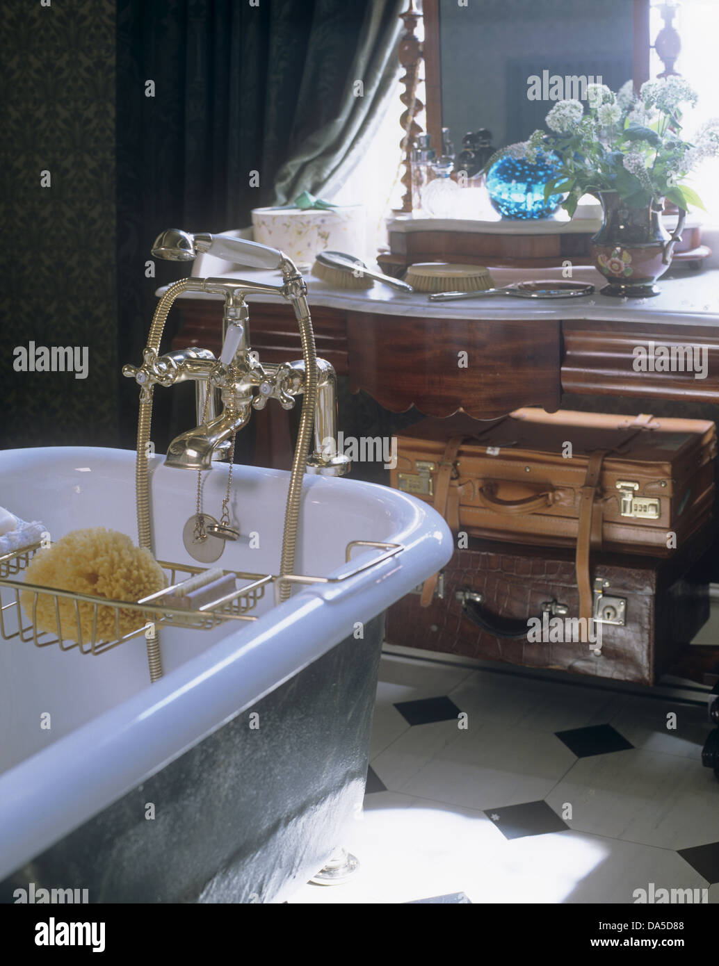 Roll-top vasca da bagno con doccia tocca il raccordo e il rack del bagno in bagno con vecchie valigie di cuoio sul tavolo della toeletta Foto Stock