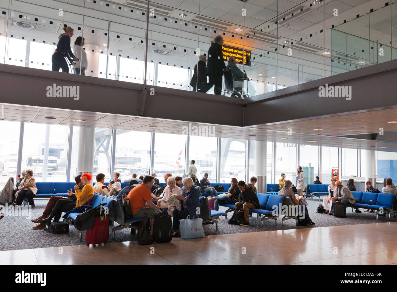 I passeggeri in attesa in aeroporto partenza lounge arrivi sotto il corridoio Foto Stock
