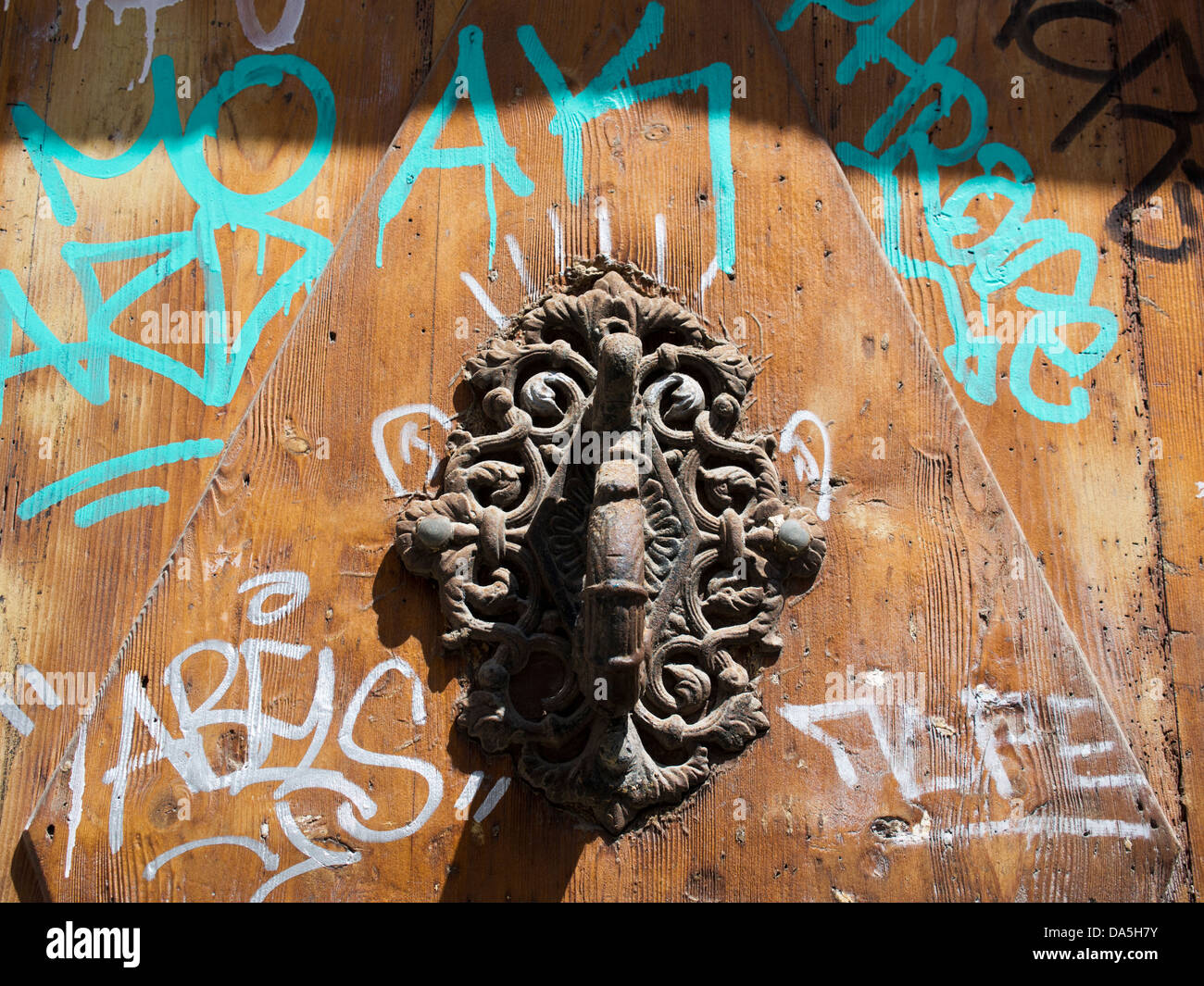 Graffiti e un ornato respingente su una porta nel quartiere Gotico di Barcellona, Spagna Foto Stock