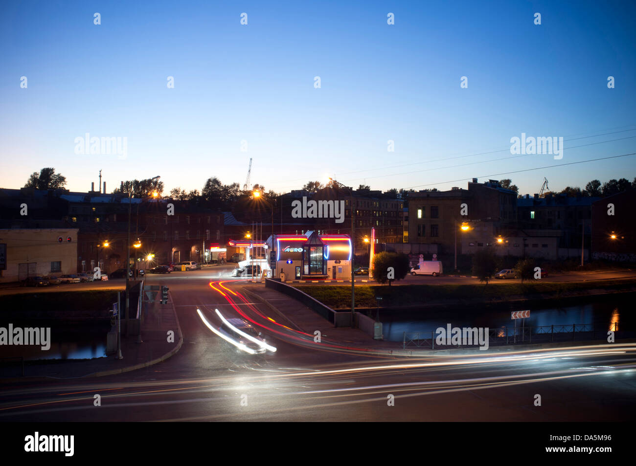 Stazione di benzina con le automobili da parte di guida di notte in una strada urbana a notte. Foto Stock