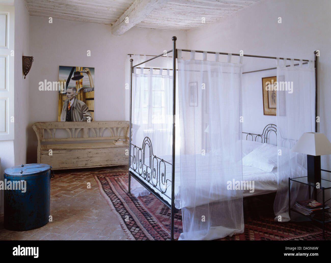 Metallo letto a baldacchino con voile bianco oscuranti in bianco paese francese camera con letto in legno antico settle Foto Stock