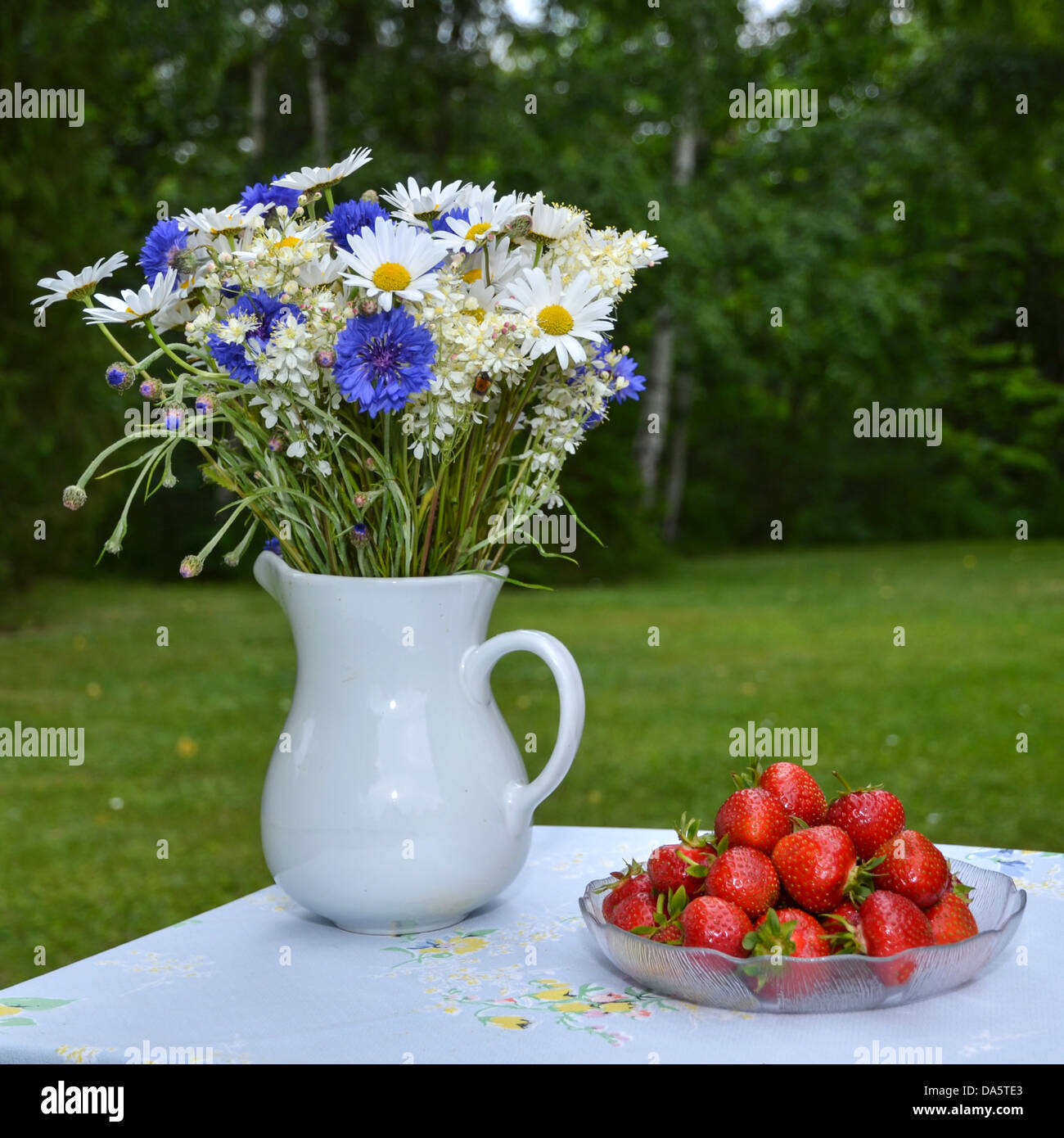 Fragole e fiori d'estate su una tabella outdorrs in un giardino Foto Stock
