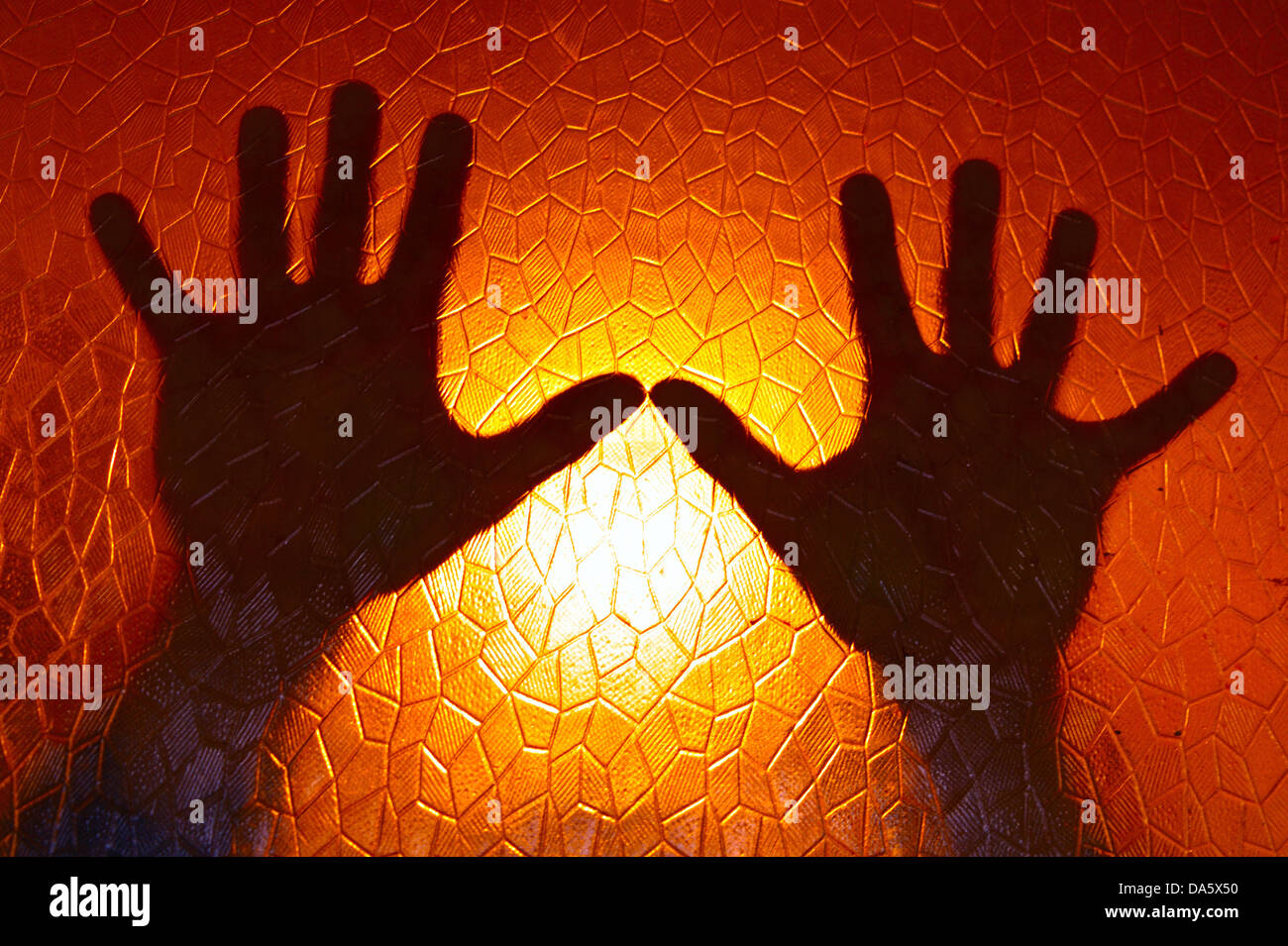 Silhouette di mani sul fuoco orange Colore di sfondo in vetro colorato con motivo geometrico cinema Horror Foto Stock