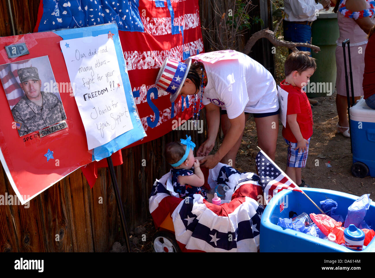 Tucson, Arizona, Stati Uniti. 04 Luglio, 2013. Celebranti nel Palo Verde quartiere partecipare al cinquantesimo quarto annuale di luglio sfilata per celebrare l anniversario dell indipendenza degli Stati Uniti in Tucson, Arizona, Stati Uniti. Laura Brockert-Gonzales, (centro), con due dei suoi tre bambini, Lillyana, dieci mesi (sinistra) e Daniel, 4, ricorda il loro marito e padre, che è stato distribuito in Afghanistan negli ultimi 6 mesi. Credit: Norma Jean Gargasz/Alamy Live News Foto Stock