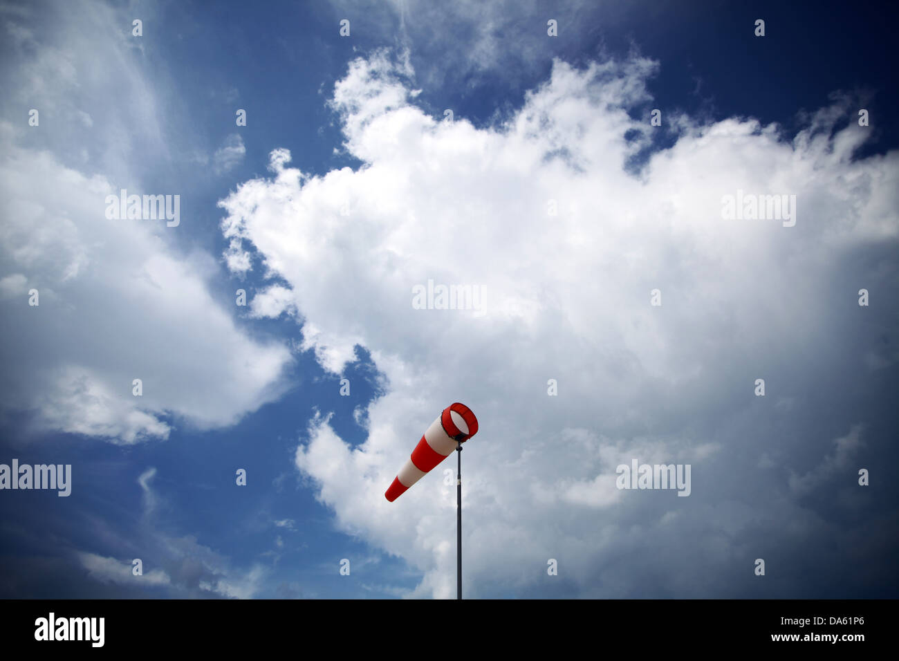 Un rosso banderuola contro un blu cielo nuvoloso Foto Stock
