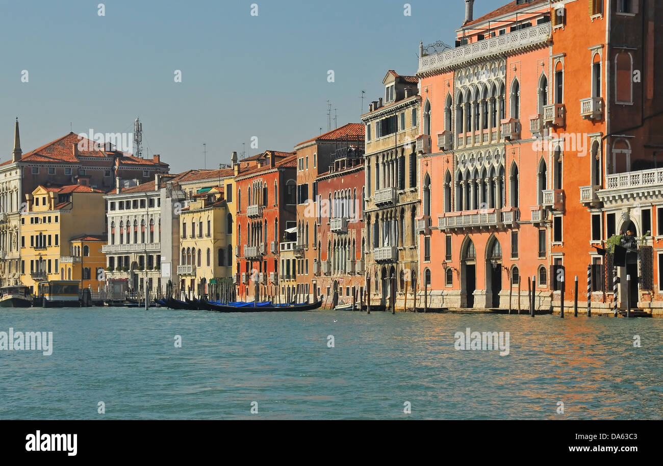 Dipinto luminosamente case e palazzi fiancheggiano il lungomare del Canal Grande di Venezia, Italia. gondole possono essere visto ormeggiati Foto Stock