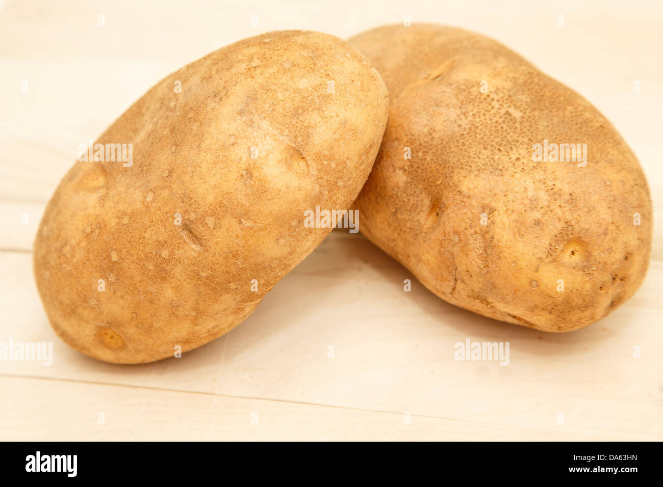 Due patate intere su un legno tagliere pronto per la cottura Foto Stock