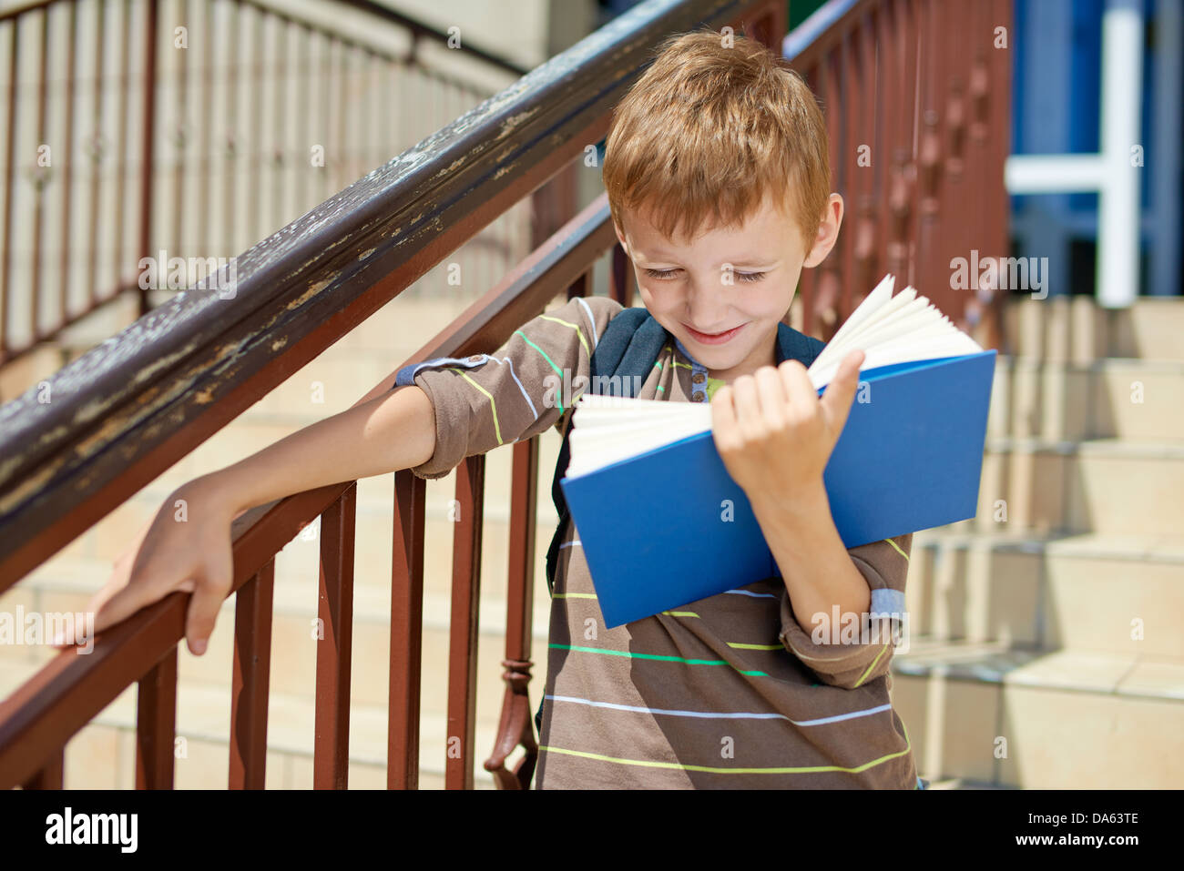 Giovane capretto felice libro sulle scale della scuola Foto Stock
