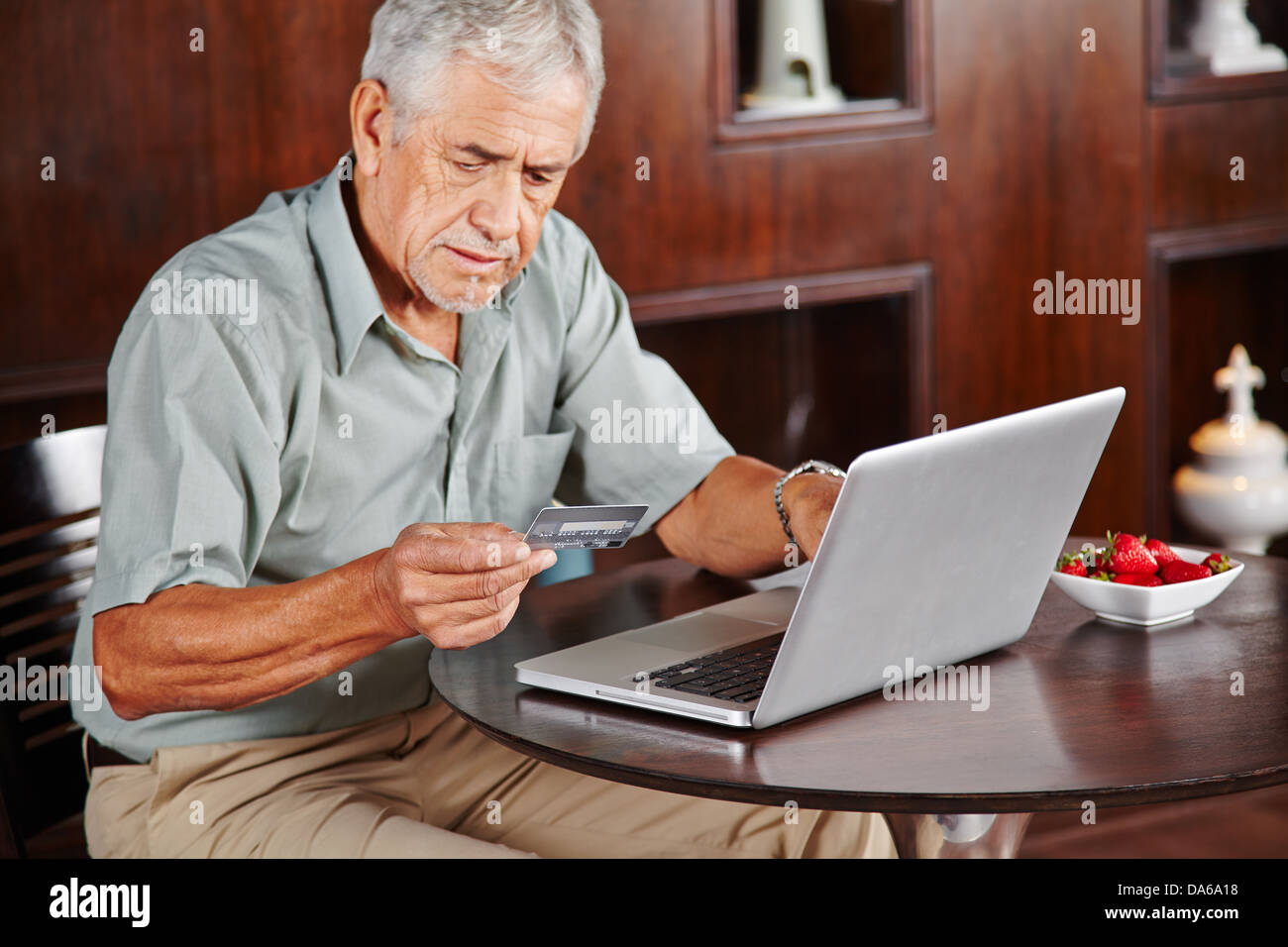 Senior man a laptop pagando con la carta di credito per gli acquisti online Foto Stock