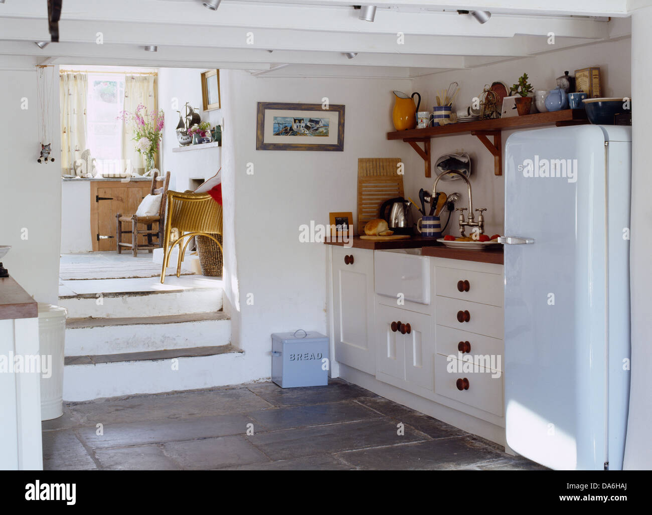 La scalinata in pietra che conduce in basso in stile country con cucina di blu pallido Smeg frigo e bandiera pavimento in pietra Foto Stock