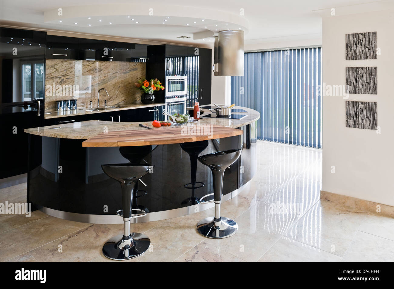 Coppia di Bomba sgabelli da bar per la prima colazione bar su nero lucido isola centrale unità nella cucina moderna con pavimento in pietra Foto Stock