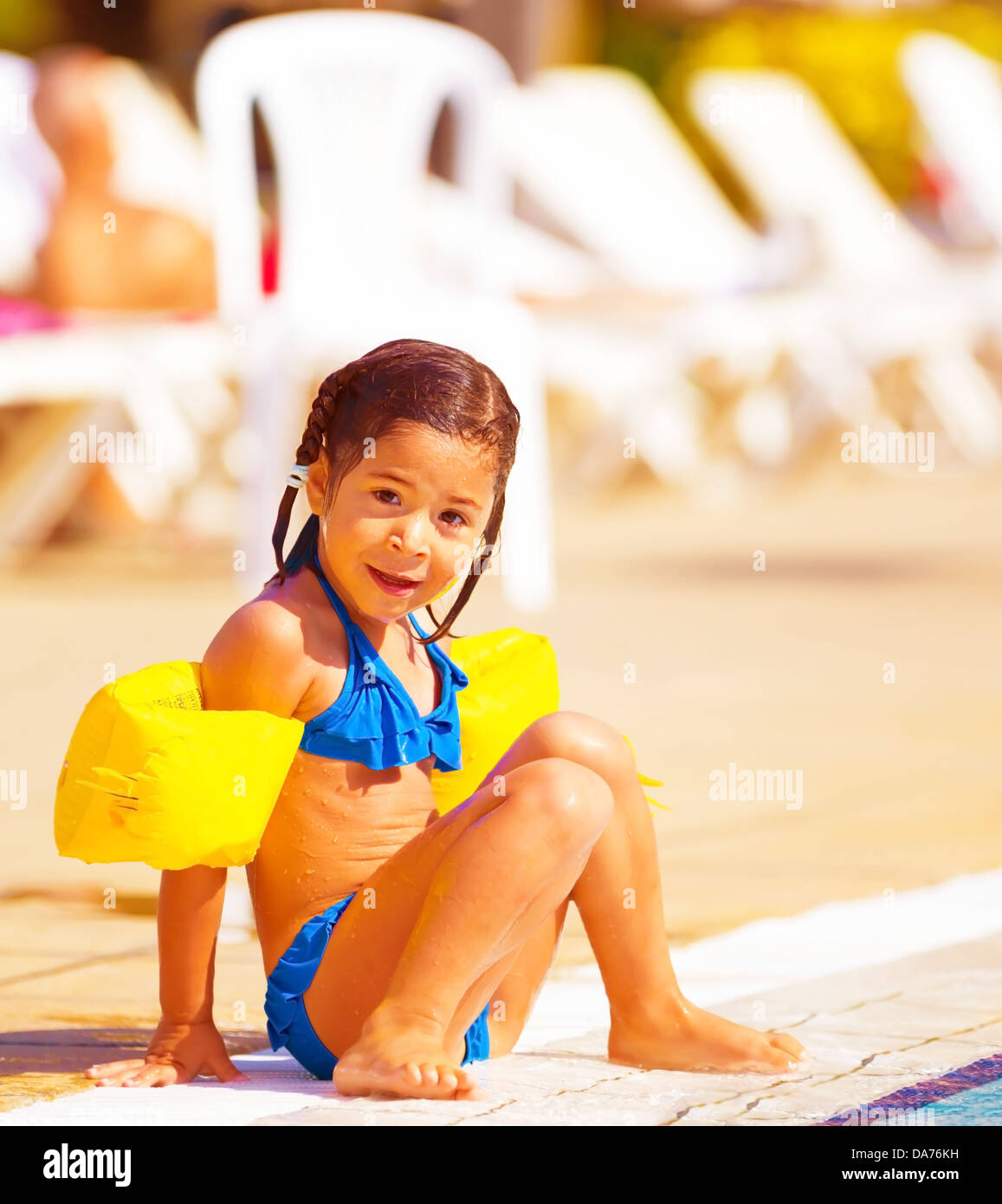 Incantevole piccola ragazza seduta vicino alla piscina, attivo infanzia felice, vacanze estive, avendo divertimento all'aperto, indossando il costume da bagno Foto Stock