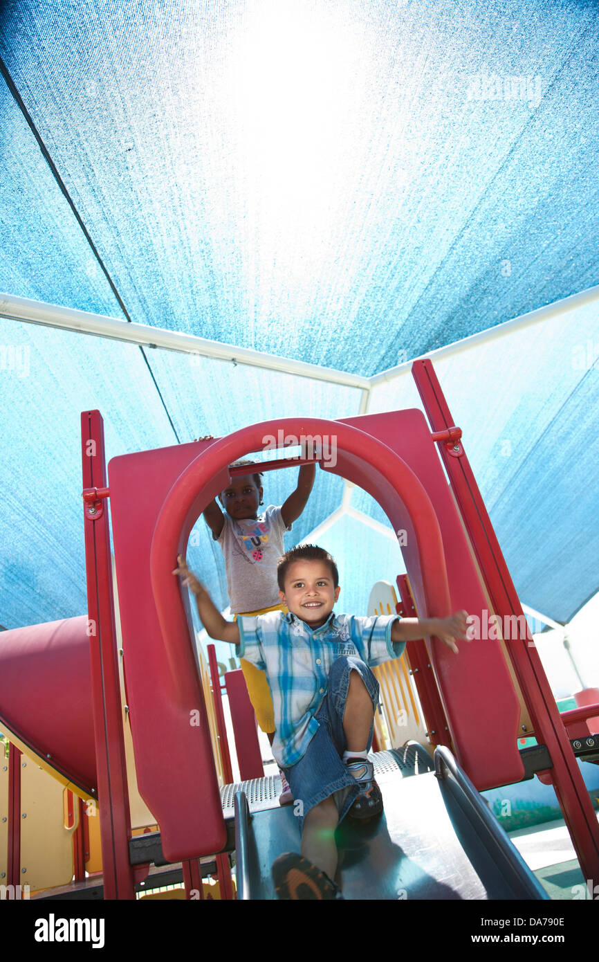 Bambini che giocano su un parco giochi slitta ispanica caucasico asain Foto Stock