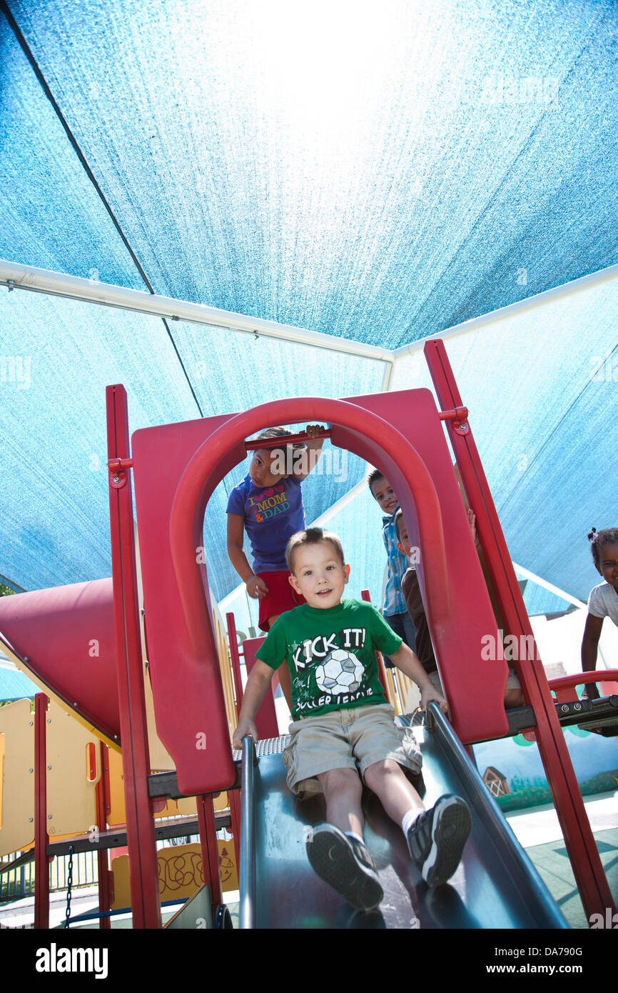 Bambini che giocano su un parco giochi slitta ispanica caucasico asain Foto Stock