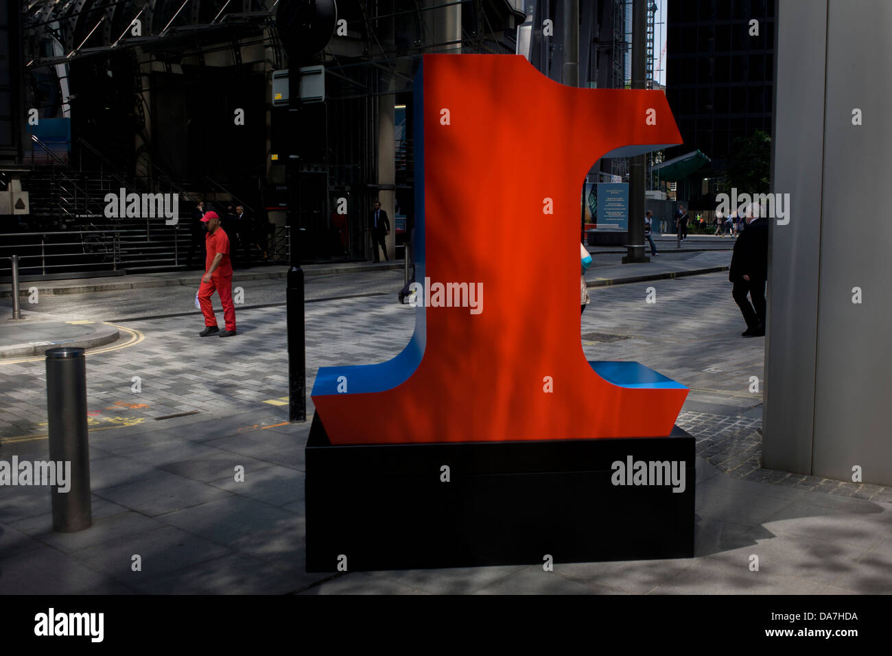 Un lavoratore in tuta rossa passa-da un grande numero di rosso uno, parte di un arte di installazione intitolata "uno a zero (i dieci numeri)' da American pop artista Robert Indiana (b 1928), in Lime Street, Città di Londra, capitale Square Mile, e il suo cuore finanziario. Foto Stock