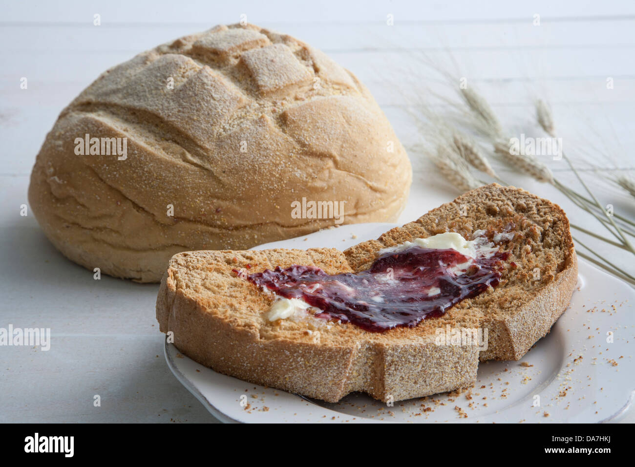 Fetta di pane fatto in casa con burro fuso e confettura di fragole Foto Stock