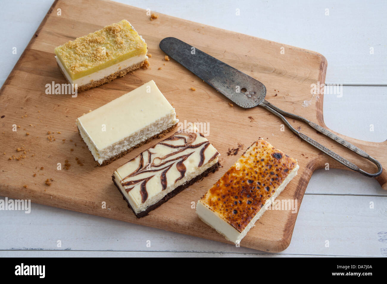 Fette di diversi dolci di ricotta su un legno tagliere con coltello di servizio Foto Stock