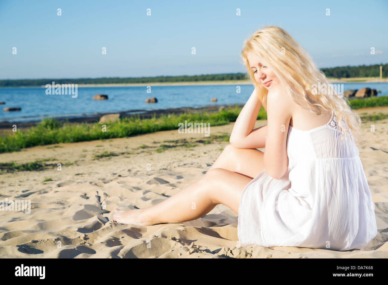 Donna in abito bianco indulgenza sulla spiaggia a caldo Foto Stock