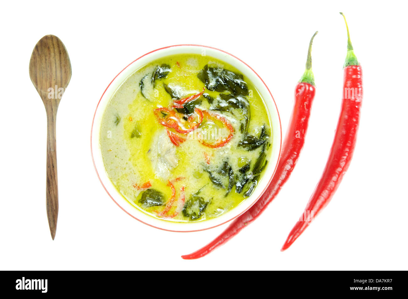 Vista superiore verde pollo al curry nella ciotola , il cucchiaio di legno peperoncino rosso , su sfondo bianco Foto Stock