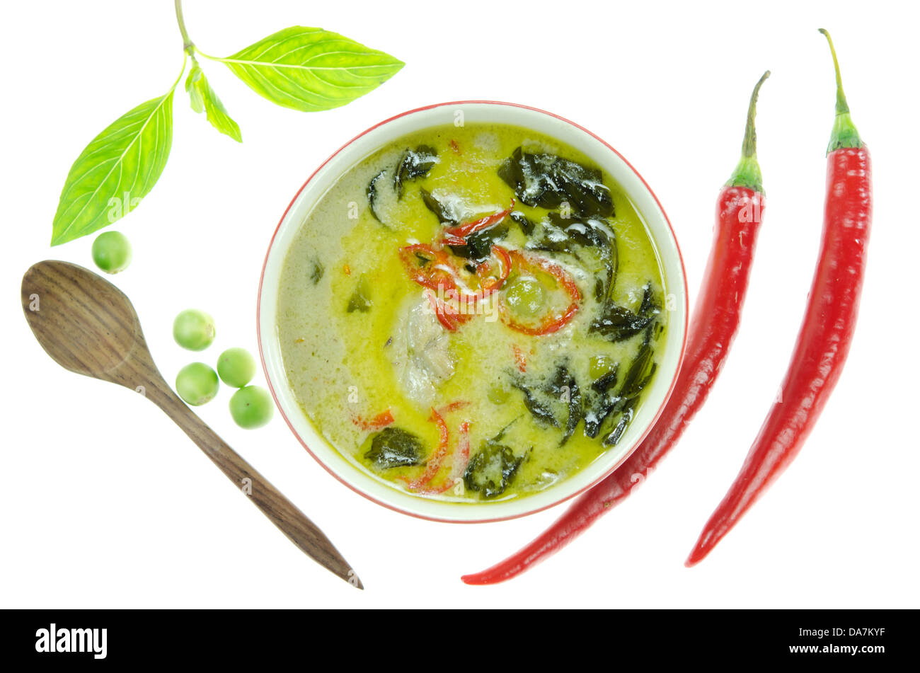 Vista superiore verde pollo al curry nella ciotola , vegetali verdi, il peperoncino rosso e il cucchiaio di legno su bianco Foto Stock