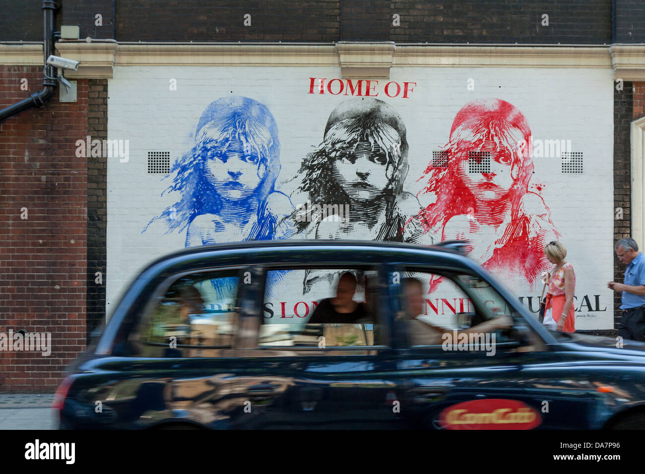 Un black cab passa davanti ad un murale per Les Miserables nel West End Foto Stock