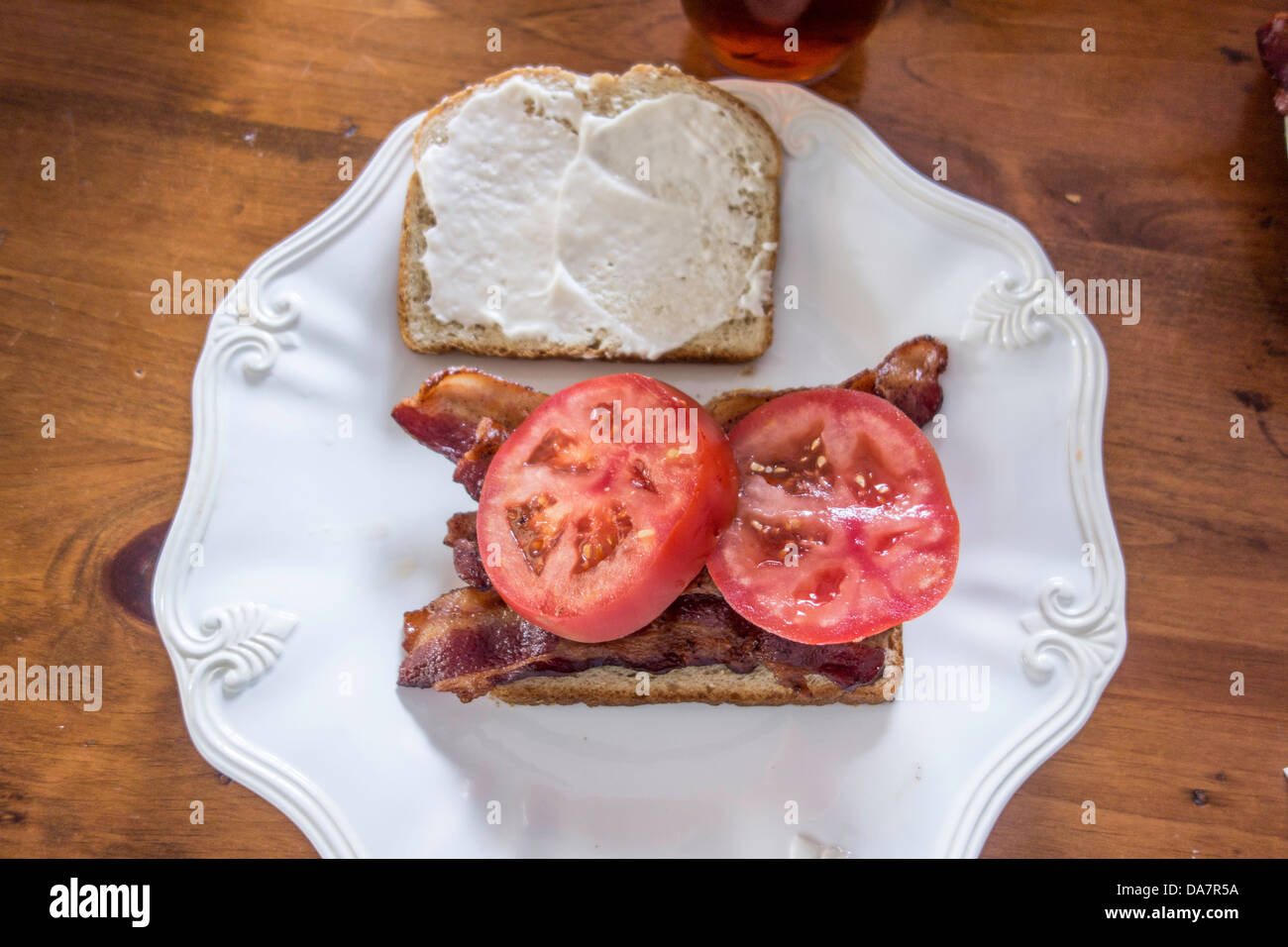 La pancetta e pomodoro sandwich con maionese seduto su una piastra bianca, su di un tavolo di legno. Stati Uniti d'America. Foto Stock