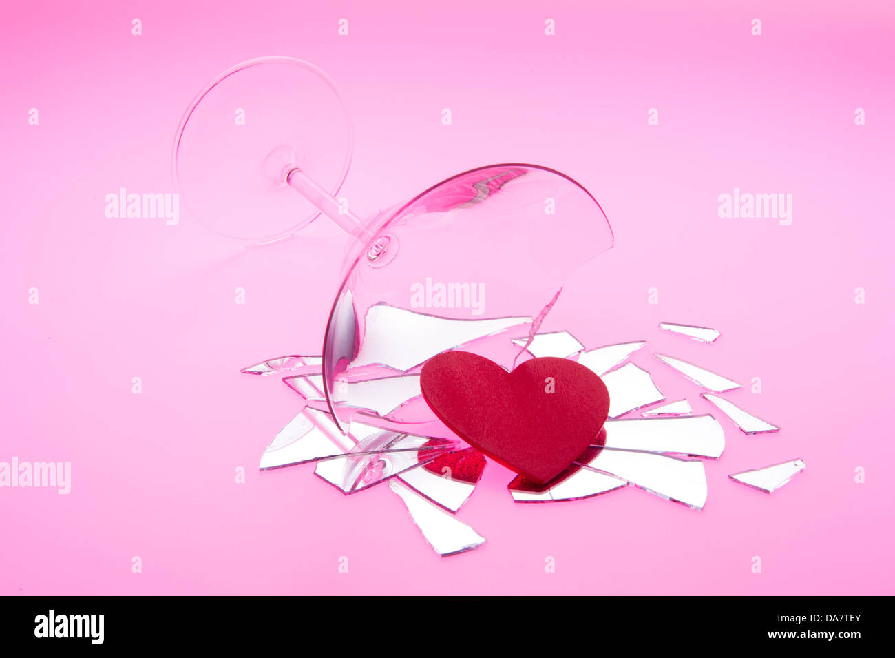Concetto foto di rapporti interrotti con cuore fuoriuscita delle rotture di martini colpo di vetro sul tavolo luminoso con luce rossa Foto Stock