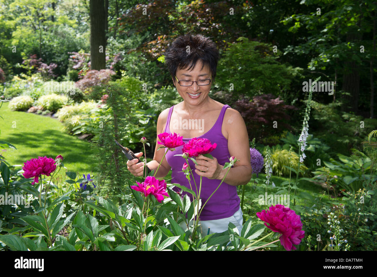 Una donna asiatica funziona nel suo bellissimo giardino Foto Stock