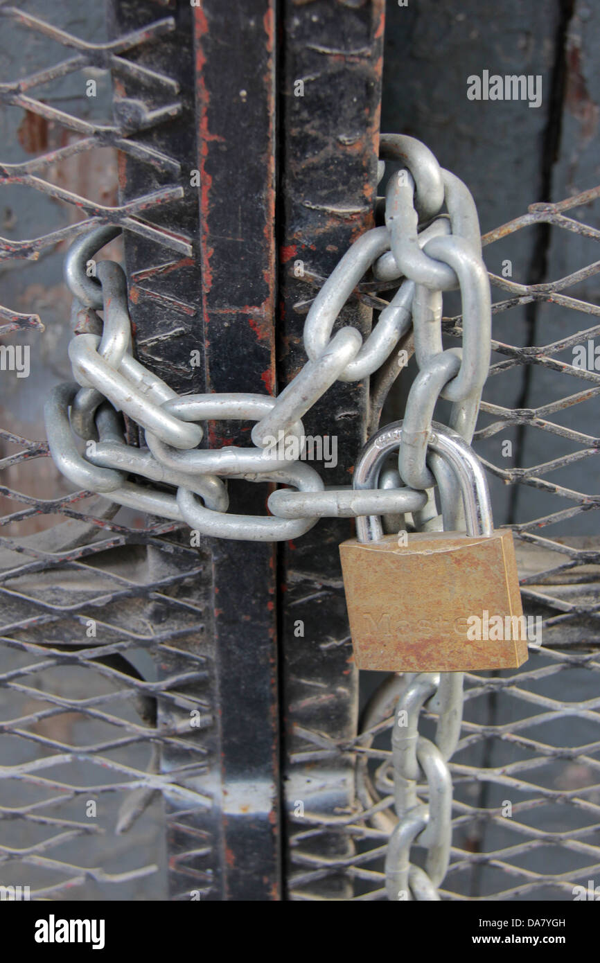 Una nuova catena e un lucchetto chiuso in un cancello di ferro e con un po'  di ruggine su di esso, le misure di sicurezza per impedire il furto Foto  stock -
