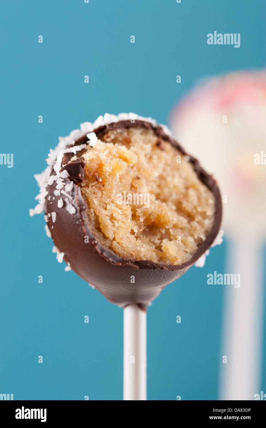 Morso topping cocco torta al cioccolato pop su sfondo blu Foto Stock