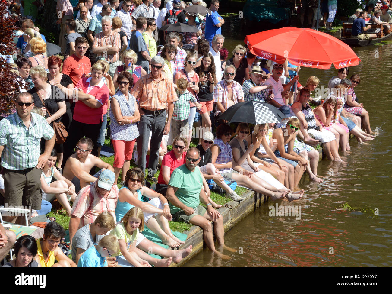 Visitatori tenere i piedi in acqua come sono in attesa per una sfilata di barche per i flussi della Spreewald (Sprea boschi) in Luebbenau, Germania, 07 luglio 2013. 40 chiatte hanno preso parte al tradizionale sfilata della Sprea boschi Festival. Foto: BERND SETTNIK Foto Stock