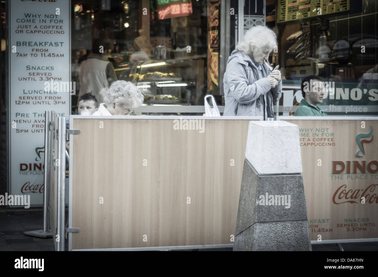 Donna accendere una sigaretta al di fuori di una caffetteria Foto Stock