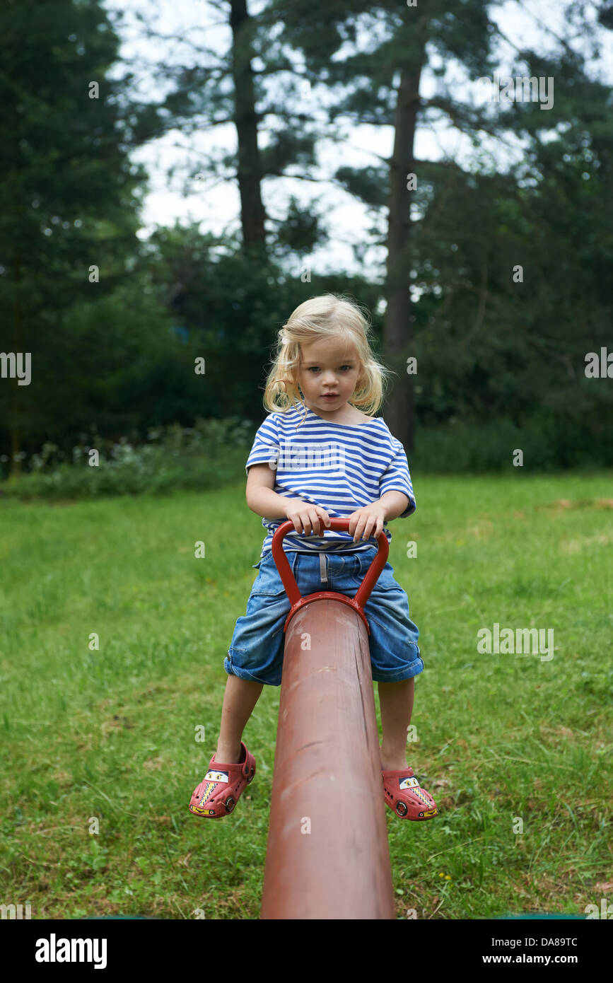 Bambino ragazza bionda che si divertono sull'altalena in un parco estate Foto Stock