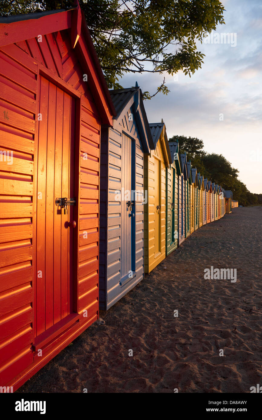 Colorato dipinto luminosamente cabine sulla spiaggia, all'alba / Alba Llanbedrog beach Llyn Peninsula Gwynedd North Wales UK Foto Stock