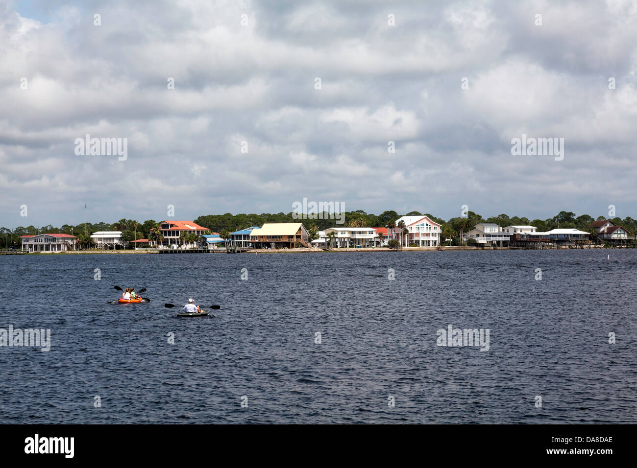 Due kayakers paddling sulle acque off Keaton Beach con una fila di case lungo la spiaggia in background. Foto Stock
