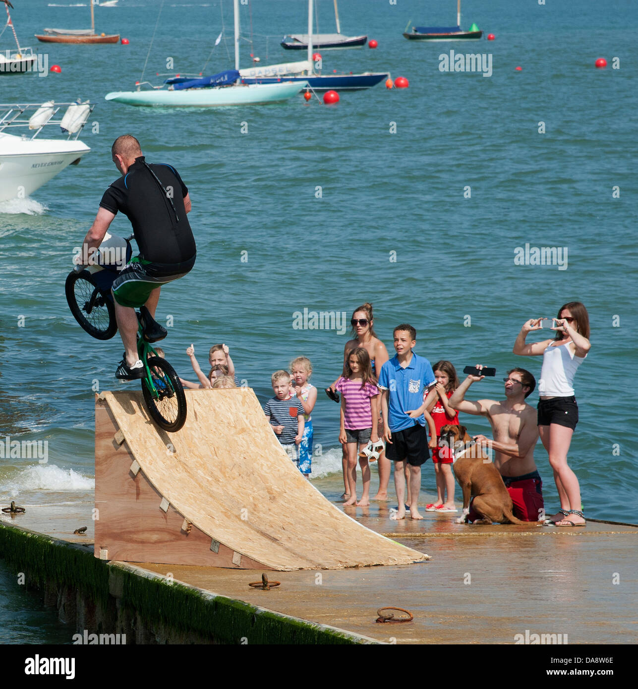 Ciclista con un tuffo nel mare da una rampa di legno. Cowes Regno Unito Inghilterra Foto Stock